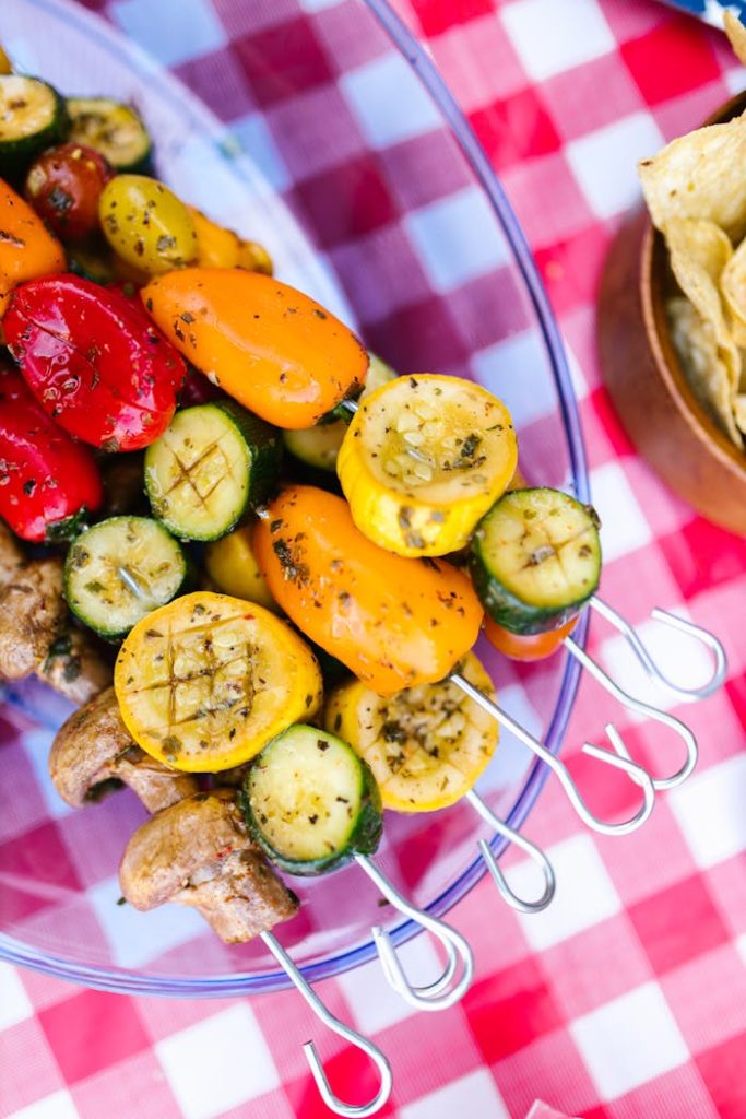 Vibrant grilled vegetable skewers on a red checkered tablecloth. Perfect for summer BBQs.